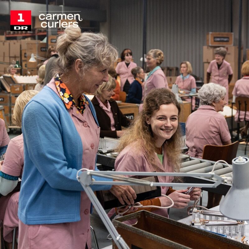 Sille Schnoor in a pink factory uniform at the assembly line in the DR series Carmen Curlers