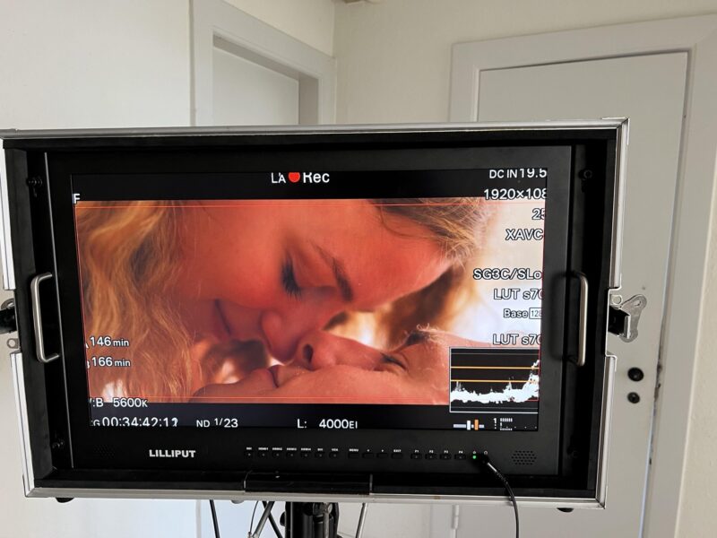 Camera monitor on a set showing a close-up scene in warm light during filming