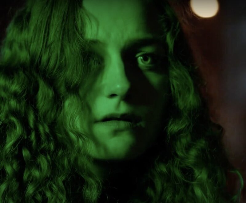Close-up of Sille Schnoor in character bathed in green light with a serious look