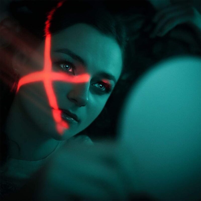Sille Schnoor in character with a red traffic light over her face in cool blue-green light
