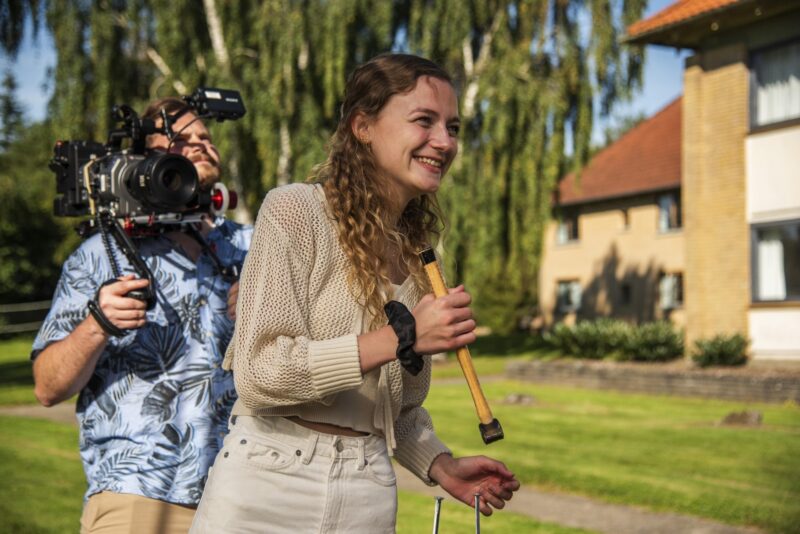 Sille Schnoor holds a boom microphone next to a photographer with a camera rig on an outdoor location