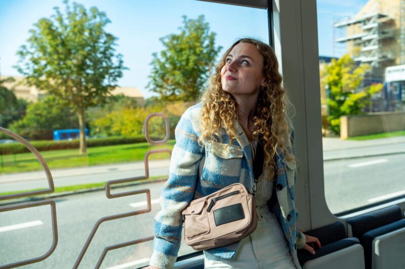 Sille Schnoor sits on a train in a blue checkered jacket and looks up at the window in backlight