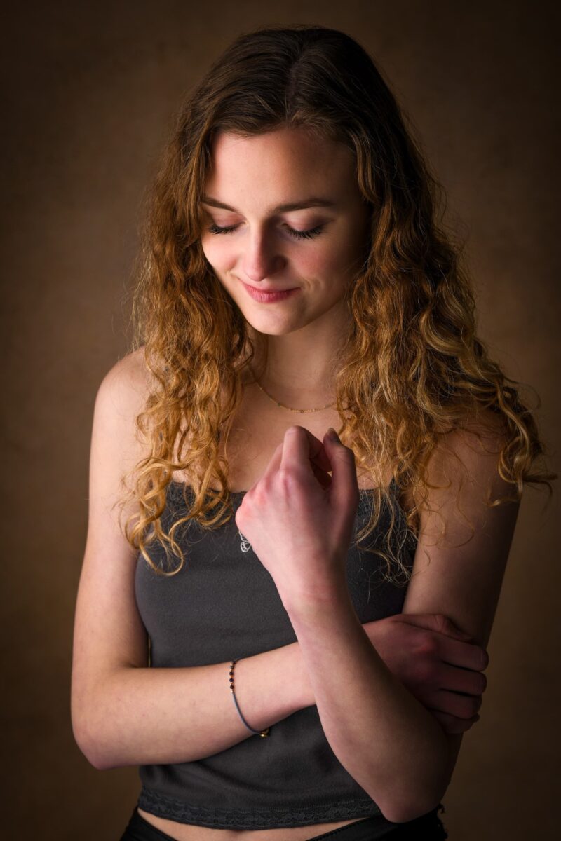 Sille Schnoor with lowered gaze in a gray top against a dark studio background