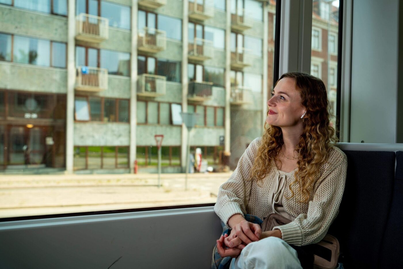 Sille Schnoor sits by a large window in a light cardigan and looks out into the daylight