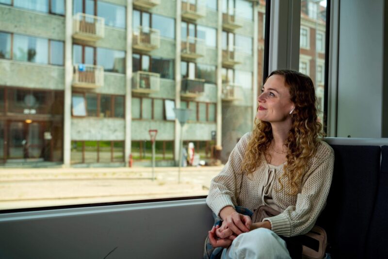 Sille Schnoor sits by a large window in a light cardigan and looks out into the daylight