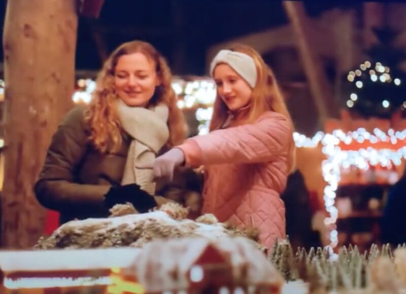 Scene from the Christmas series Valdes Jul with Sille Schnoor at a lit-up Christmas stall